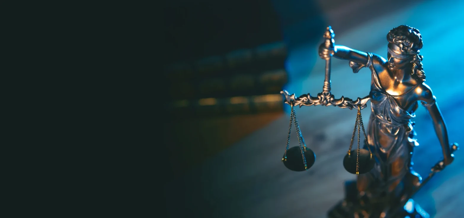 Bronze Lady Justice holding scales against a blue background